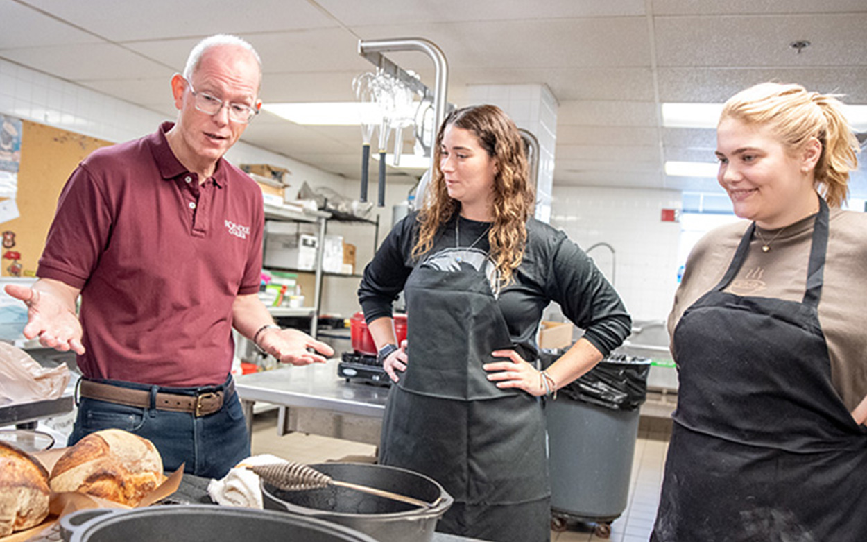 Students talk with their professor over freshly baked bread loaves