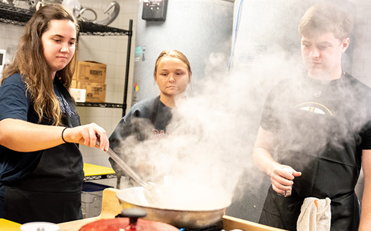 Students stir a pan issuing billows of steam